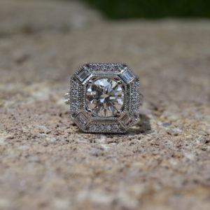 Custom designed round diamond halo engagement ring with baguette diamonds in platinum