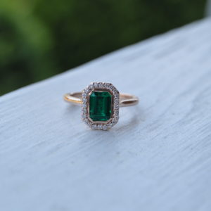 Custom designed emerald cut emerald with diamond halo engagement ring in rose gold