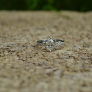 Oval diamond engagement ring with channel set round diamonds in the shank in white gold