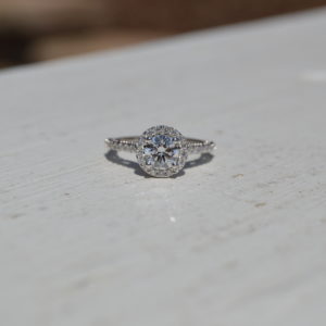 Custom designed round diamond halo engagement ring with round diamonds set with shared prongs in the shank