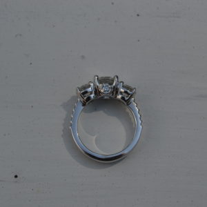 Custom designed lady's three round diamond ring with round shared prong diamond shank and diamond peek a boo in white gold